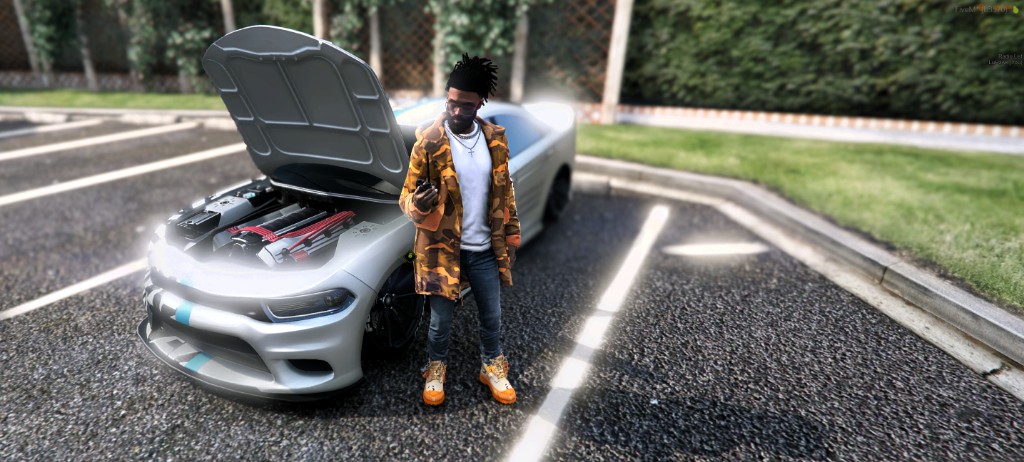 Lu Hawk standing beside a silver car with the hood open